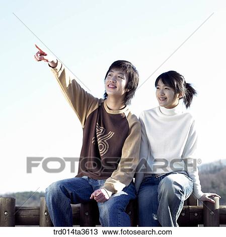 Teens with smile pointing at sky on siitng on the fence View Large Photo Image Stock Image - Teens with smile pointing at sky on siitng on the fence. Fotosearch