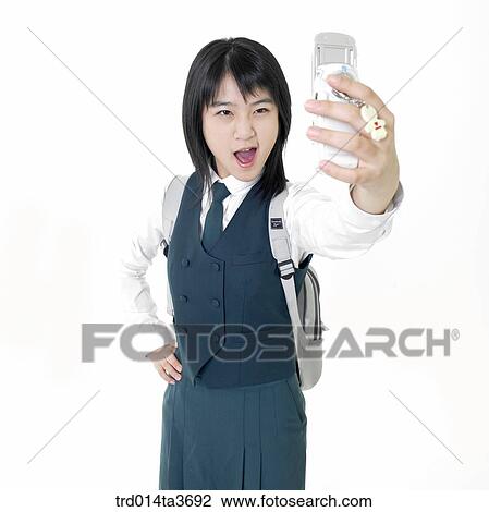 Stock Image - Teen girl in uniform taking picture with her cell phone camera. Fotosearch