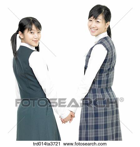 Stock Image - Teen girls holding their hands and looking back. Fotosearch