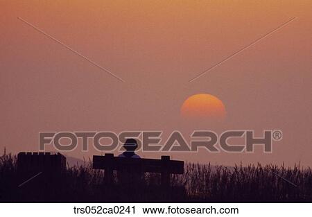 Stock Image - Jeju Island/ people on the bench, glow scene, sunset. Fotosearch