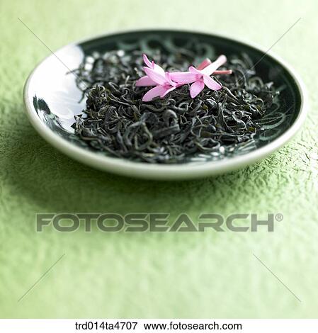 Stock Photo - Green tea leaves on the plates and teapot. Fotosearch