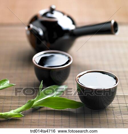 Stock Photograph - Teacup and teapots decorated with green leaf, art of tea making. Fotosearch