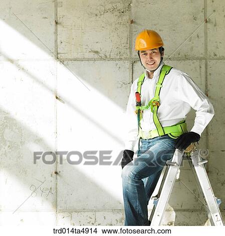 Picture - at a construction place, a worker sitting on a ladder. Fotosearch