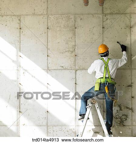 at a construction place, a worker working on a ladder View Large Photo Image Stock Image - at a construction place, a worker working on a ladder. Fotosearch