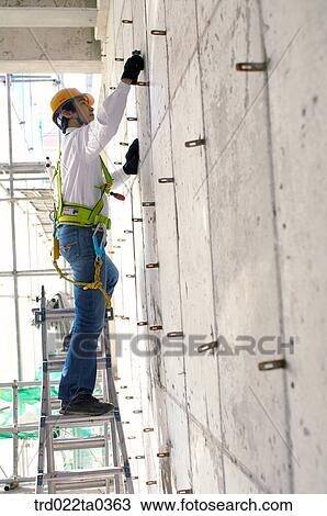 at a construction place, a worker working on a ladder View Large Photo Image Stock Image - at a construction place, a worker working on a ladder. Fotosearch