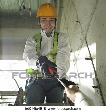 Stock Photo - at a construction place, a worker working with a driver. Fotosearch