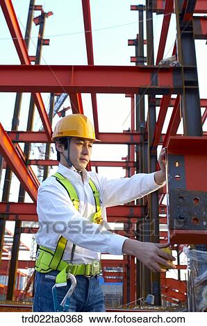 at a construction place, a worker holding construction equipment View Large Photo Image Stock Photo - at a construction place, a worker holding construction equipment. Fotosearch