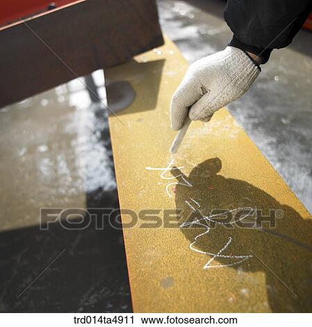 Stock Image - at a construction place, a worker's hand marking on an reinforcing rod. Fotosearch