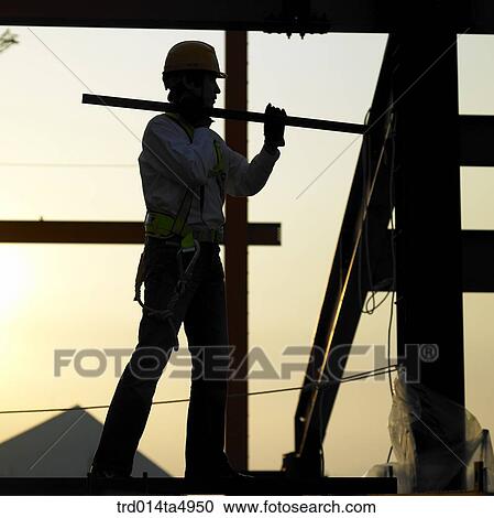 Stock Image - at a construction place, a worker's silhouette. Fotosearch
