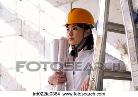 Picture - at a construction place, an architect holding a plan. Fotosearch