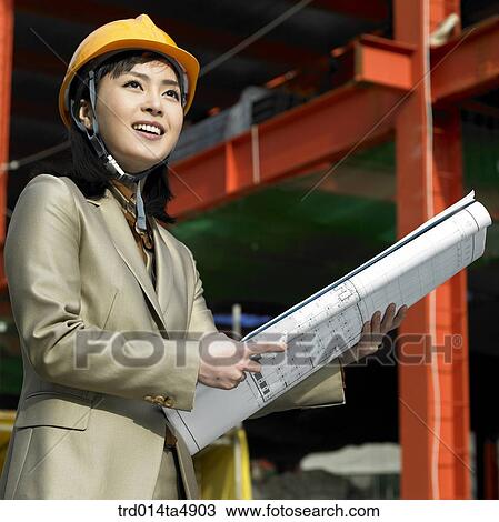 Stock Image - at a construction place, an architect looking at a plan. Fotosearch