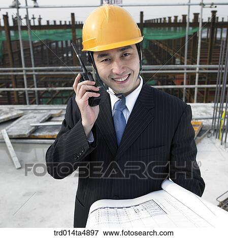 at a construction place, an architect looking at a plan and talking with a radiotelegraph View Large Photo Image Stock Photo - at a construction place, an architect looking at a plan and talking with a radiotelegraph. Fotosearch