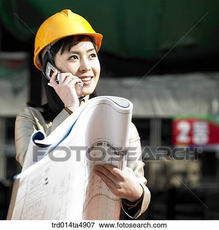 at a construction place, an architect looking at a plan and talking on the phone View Large Photo Image Stock Photo - at a construction place, an architect looking at a plan and talking on the phone. Fotosearch