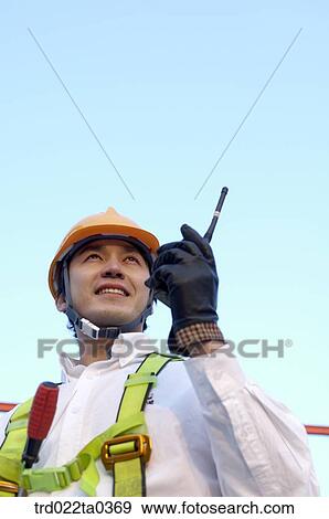 Stock Photo - at a construction place, an architect talking on a radiotelegraph. Fotosearch