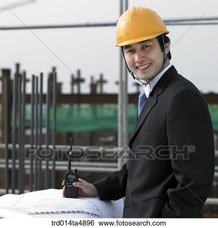 Stock Photograph - at a construction place, an architect looking at a plan. Fotosearch