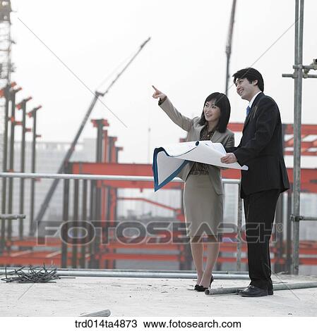 Stock Image - at a construction place, architects discussing about a plan. Fotosearch
