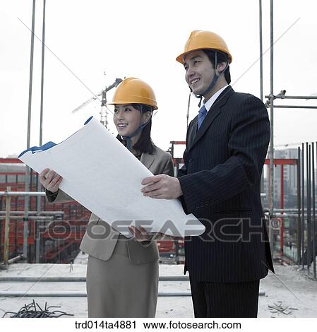 Stock Image - at a construction place, architects discussing about a plan. Fotosearch