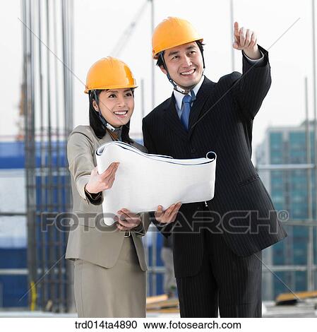 Stock Image - at a construction place, architects discussing about a plan. Fotosearch