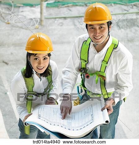 Stock Image - at a construction place, architects discussing about a plan. Fotosearch