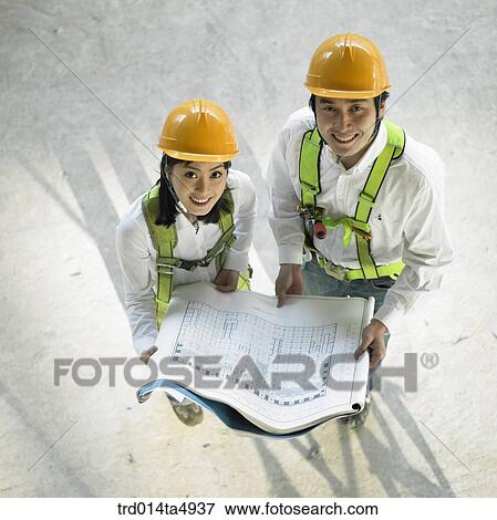 at a construction place, architects holding a plan View Large Photo Image Stock Photo - at a construction place, architects holding a plan. Fotosearch