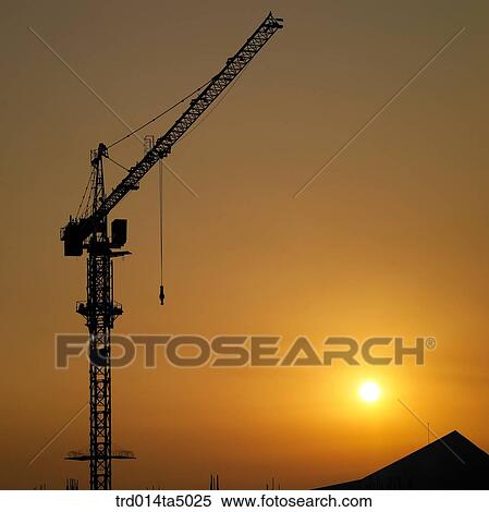 Stock Photography - at a construction place, a construction machinery with the glow of the setting sun. Fotosearch