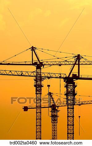 Stock Image - at a construction place, a crane with the glow of the setting sun. Fotosearch