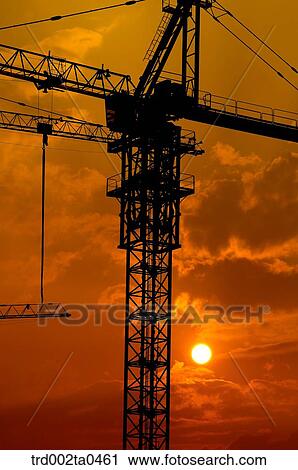 Stock Image - at a construction place, a crane with the glow of the setting sun. Fotosearch