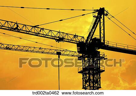 Stock Image - at a construction place, a crane with the glow of the setting sun. Fotosearch