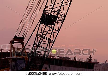 at a construction place, a crane with the glow of the setting sun View Large Photo Image Stock Photo - at a construction place, a crane with the glow of the setting sun. Fotosearch