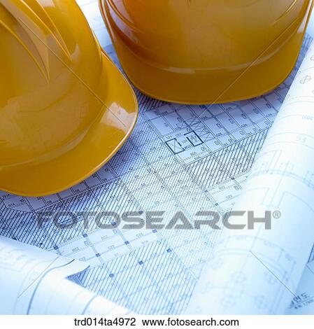 Stock Image - construction, a plan and a safety hat on a desk. Fotosearch