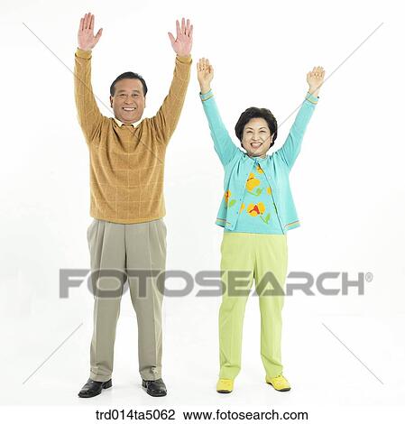 Stock Image - Family/ an friendly old couple holding up their hands. Fotosearch