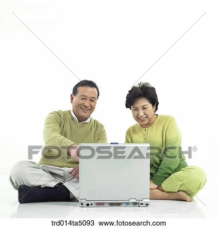 Stock Image - The old/ an sitting old couple working with a notebook. Fotosearch