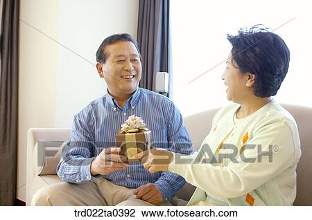 a wife giving a present to her husband View Large Photo Image Stock Image - a wife giving a present to her husband. Fotosearch