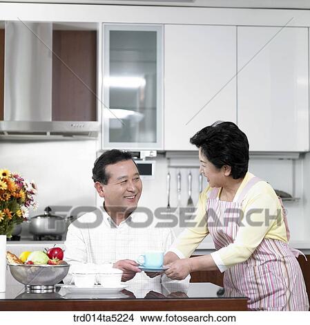 Picture - a wife taking a cup of tea to her husband. Fotosearch