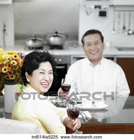 Stock Photography - an old couple drinking wine at a kitchen. Fotosearch