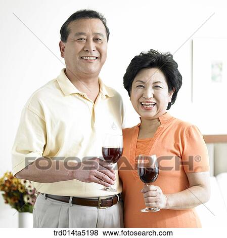 Stock Photo - an old couple drinking wine on a bed. Fotosearch