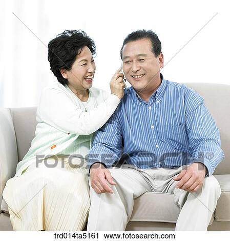 Stock Image - an old couple on a sofa listening to music. Fotosearch