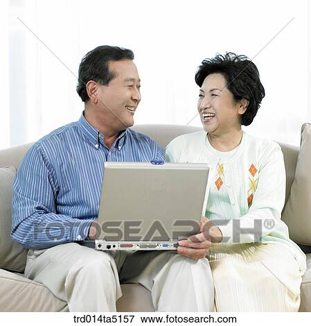 Stock Photo - an old couple with a notebook on a sofa. Fotosearch