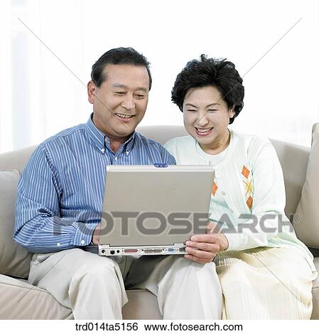 Stock Photograph - an old couple with a notebook on a sofa. Fotosearch