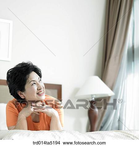 Picture - an old woman on a bed. Fotosearch