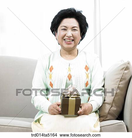 an old woman with a present box on a sofa View Large Photo Image Picture - an old woman with a present box on a sofa. Fotosearch