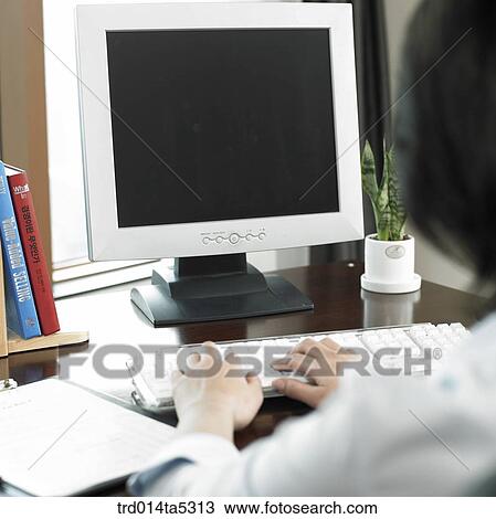 Stock Image - a back working with a computer. Fotosearch