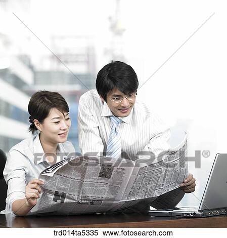 a businessman and a businesswoman reading a newspaper View Large Photo Image Stock Photography - a businessman and a businesswoman reading a newspaper. Fotosearch