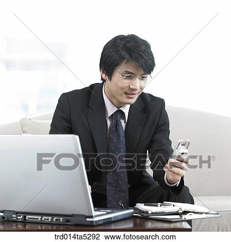 a businessman looking at a mobile phone View Large Photo Image Stock Image - a businessman looking at a mobile phone . Fotosearch