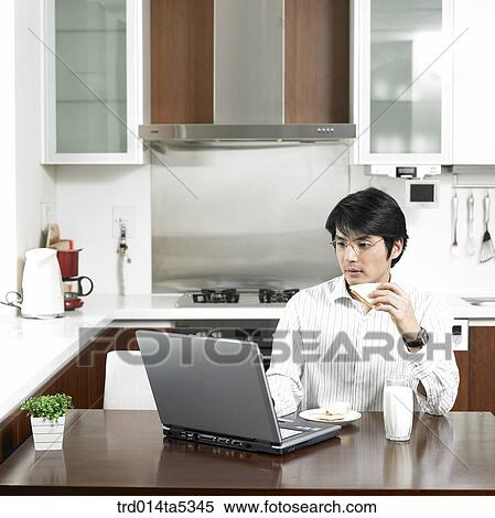 a businessman looking at a notebook at a kitchen View Large Photo Image Stock Photography - a businessman looking at a notebook at a kitchen. Fotosearch