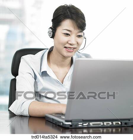 a businessman looking at a notebook with a headset View Large Photo Image Picture - a businessman looking at a notebook with a headset. Fotosearch