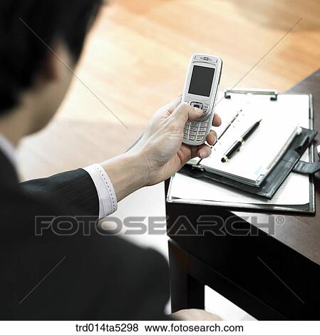 a businessman working with a diary and a mobile phone View Large Photo Image Stock Photo - a businessman working with a diary and a mobile phone. Fotosearch