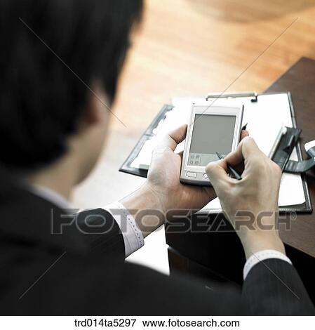 Stock Photo - a businessman working with a PDA and a diary. Fotosearch