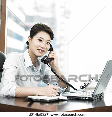 a businesswoman talking on a phone at an office View Large Photo Image Stock Photo - a businesswoman talking on a phone at an office. Fotosearch