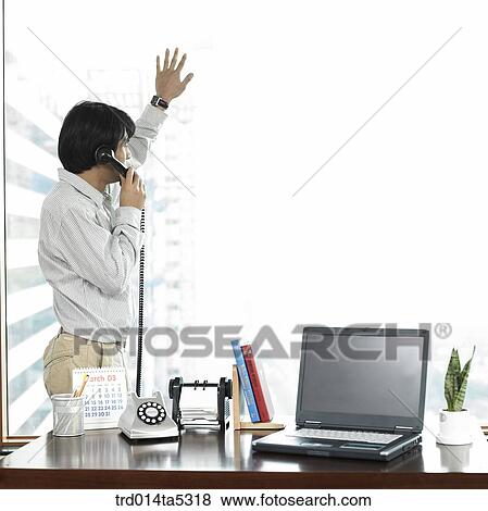 a businesswoman talking on a phone by a window View Large Photo Image Stock Photo - a businesswoman talking on a phone by a window. Fotosearch